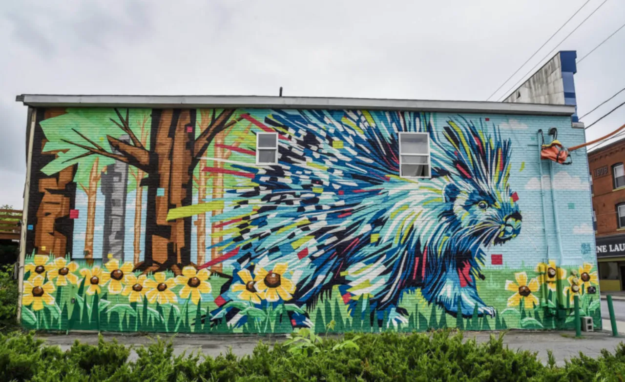 A bright and vibrant mural of a porcupine walking in a colorful forest.